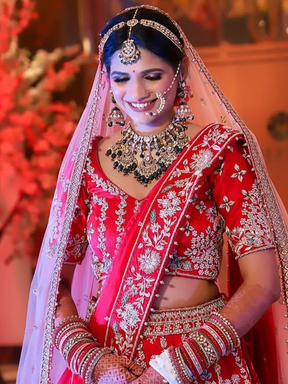 Our royal queen in a red lehenga, wearing a heavy polki and green bead set.