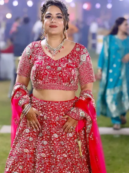 The full view of the red lehenga party look. The makeup is designed to be bold and beautiful for the special occasion.