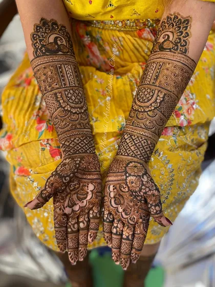 A full bridal mehendi with peacock motifs. The design is intricate and covers the hands and arms in a classic and elegant style.