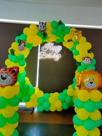 A simple and fun circular balloon arch in green and yellow with jungle animal foil balloon accents.