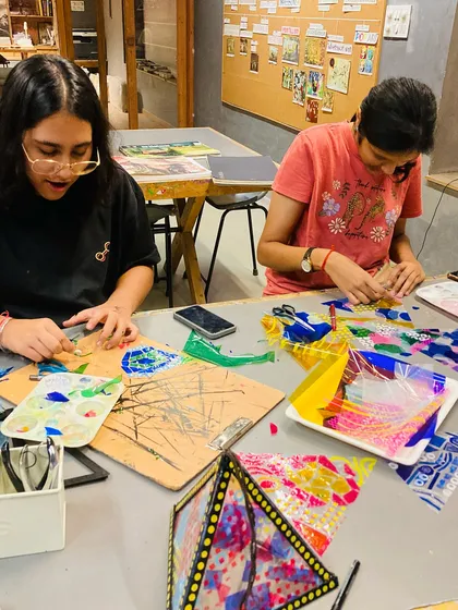 Two students collaborate and share ideas during our festival of lights workshop. Our classes encourage teamwork and creative exchange.