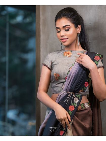 A unique half and half saree featuring earthy tones of brown, grey, and black. The saree is belted with a tie, and the pallu is adorned with floral embroidery.