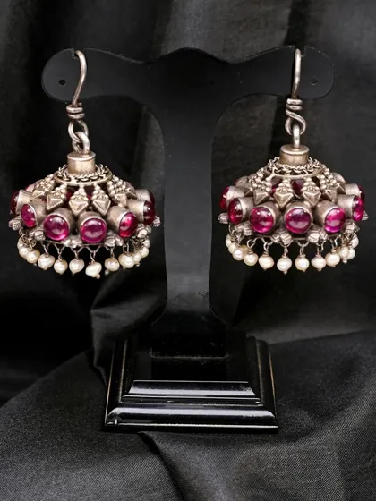 The silver jhumkhas with red stones and pearl drops, a classic design in Indian traditional jewellery.