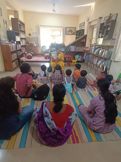 A wide shot showing the full group, including several parents, enjoying a story session. Our space is designed to be welcoming for everyone.