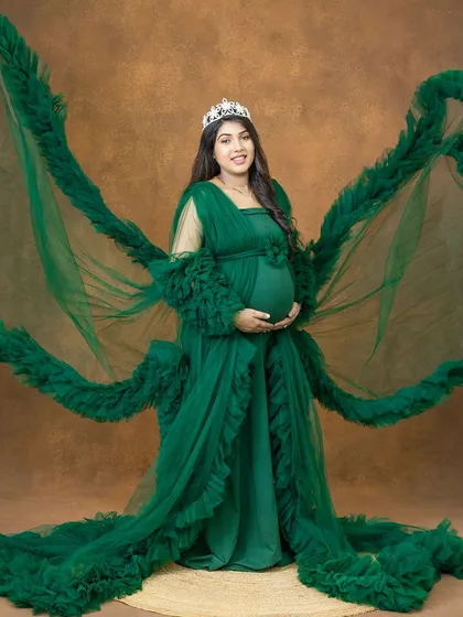 A full-length view of our stunning green ruffled gown with its dramatic "wings". This is a perfect choice for moms who want a bold, high-fashion maternity photoshoot.