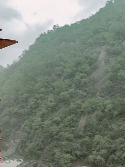 A wide shot showing the bride-to-be on a traditional balcony, with the vast, misty mountain range creating a stunning and dramatic backdrop.