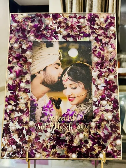 A beautiful rectangular photo frame made with preserved purple orchid petals and pearls. The couple's photo is surrounded by the delicate flowers from their wedding, creating a unique and personal keepsake.