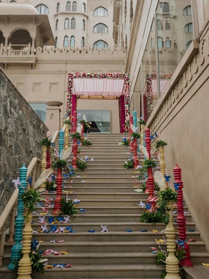 The grand staircase leading to the Mehendi is decorated with colorful pillars and scattered paper pinwheels, transforming it into a vibrant pathway.