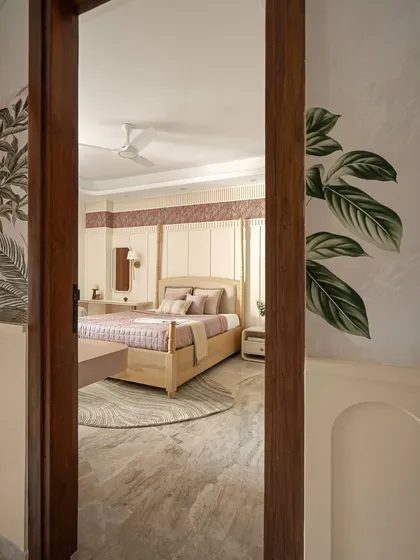 A glimpse into the bedroom through a wooden doorway, revealing a space that is serene and filled with soft, natural light.