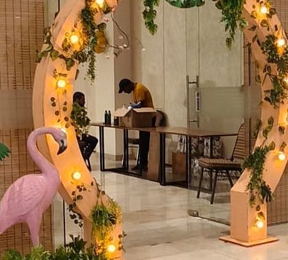 An elegant entrance arch for a jungle party, decorated with soft lighting, hanging vines, and 3D props like a flamingo and a lion cub.