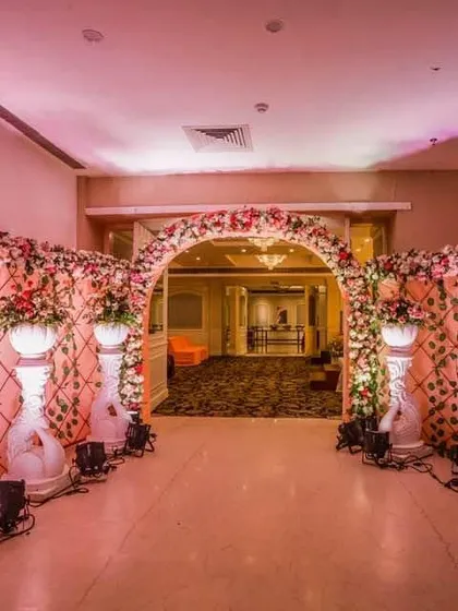 This beautiful floral entranceway was designed for an indoor event, using pink and white flowers on a lattice structure. The pathway is lined with decorative pillars and uplighting to create a warm and welcoming passage for guests.