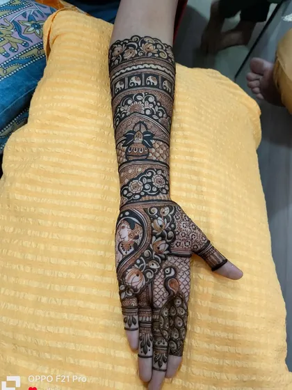 A single-hand view of a complex bridal design, showing the level of detail in every element, from the peacock to the elephant procession.