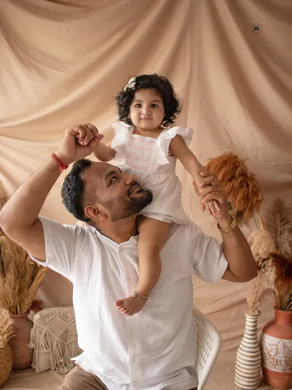 A playful father-daughter moment. A shoulder ride is always a fun way to capture genuine smiles and a loving connection.