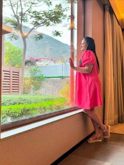 A guest enjoys the stunning view of Nandi Hills from the large window of her suite. Our rooms are designed to bring the beauty of the outdoors inside, creating a constant connection with nature.