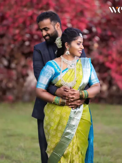 An elegant outdoor portrait of the newly engaged couple. The contrast between her bright saree and the rich red foliage creates a stunning visual for their engagement album.