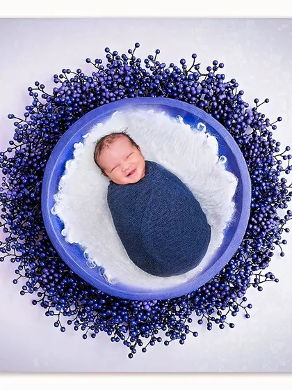 That fleeting, sleepy smile is one of the moments I live to capture. This classic swaddled portrait shows the pure bliss of a newborn, surrounded by a beautiful wreath of color.