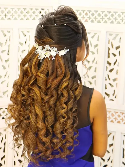 An engagement look with soft curls and a half-updo. The hair is beautifully styled to create a romantic and elegant look, perfect for celebrating a special milestone.