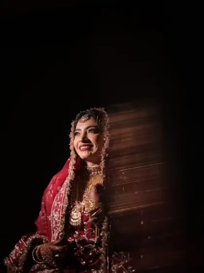 A candid moment of happiness. The bride's radiant smile is captured with creative lighting, creating a beautiful play of light and shadow that feels both artistic and genuine.