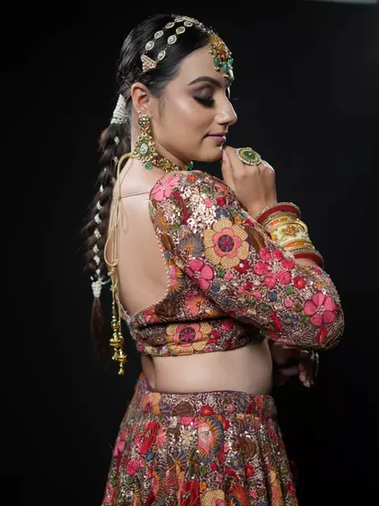 A detailed shot of the back of a bridal hairstyle. The long, thick braid is beautifully crafted and accessorized, offering a stunning view from every angle for this floral-themed bridal look.