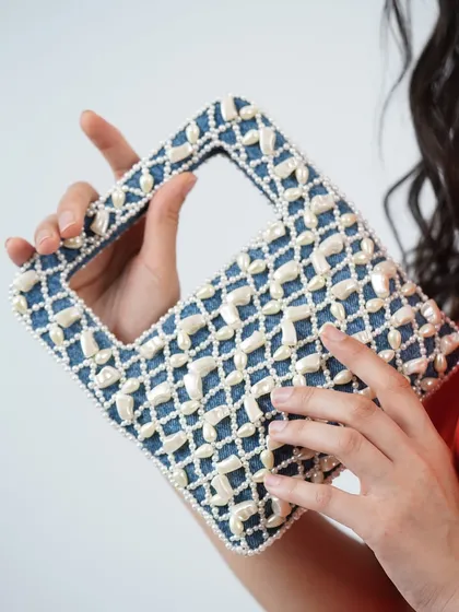 I believe in mixing classic materials in new ways. This wrist bag combines timeless denim with a beautiful lattice of hand-stitched pearls, creating a unique statement piece that's both casual and elegant.