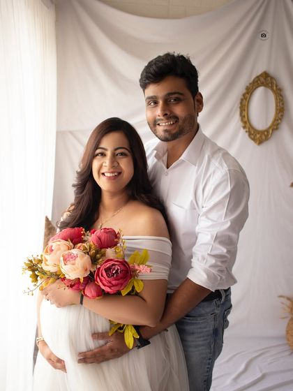 A happy couple portrait. Her white off-the-shoulder gown and the colorful bouquet create a fresh and joyful atmosphere for this pregnancy photoshoot.