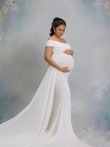 A serene and angelic portrait in a flowing white gown against a soft, painted backdrop.