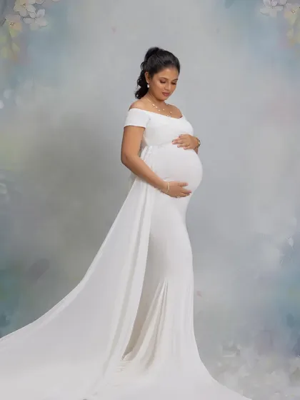 A serene and angelic portrait in a flowing white gown against a soft, painted backdrop.