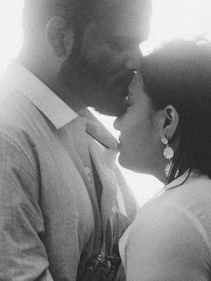 A tender, intimate moment frozen in time. This grainy black and white photograph captures the gentle emotion of a forehead kiss, focusing on the connection and love between the couple.