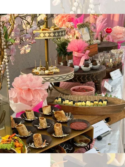 A pink themed party setup with a variety of bite sized appetizers. We included spring rolls, paneer skewers, and mini tacos, all beautifully arranged with floral and pearl decorations.