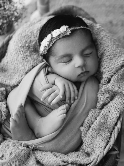 A sleeping angel in a woven basket. The delicate floral headband adds a sweet, gentle touch to this classic newborn photo.