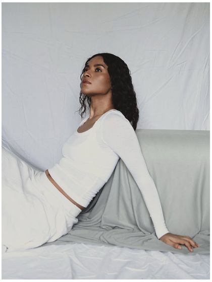 This is an example of a minimal, clean studio portrait. The all-white styling and simple draped background keep the focus entirely on the model. The lighting is soft and diffused, creating a serene and ethereal mood.