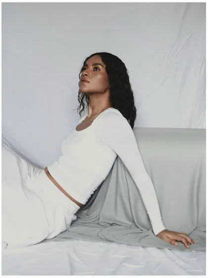 This is an example of a minimal, clean studio portrait. The all-white styling and simple draped background keep the focus entirely on the model. The lighting is soft and diffused, creating a serene and ethereal mood.