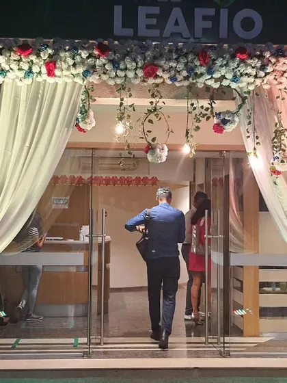 This entrance for a corporate office event for 'Leafio' combines elegant drapery with a lush floral arch. The hanging lights and greenery add a touch of sophistication, welcoming guests in style.