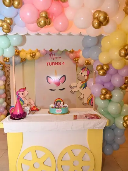 A magical unicorn-themed cake station, complete with a custom cart, pastel balloon decorations, and adorable unicorn cutouts. It's the perfect sweet spot for a whimsical birthday party.
