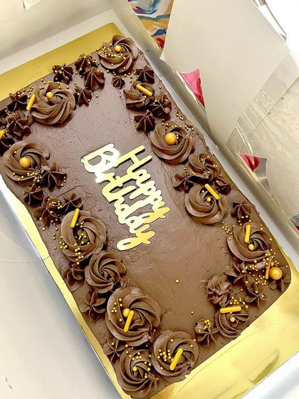 A rectangular chocolate truffle cake made for a large birthday gathering. I decorated it with intricate piping, gold sprinkles, and a "Happy Birthday" topper.