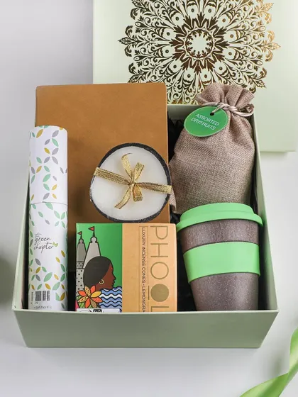 An eco-friendly Diwali hamper for the conscious consumer. It includes a reusable coffee cup, a coconut shell candle, and other sustainable goodies, all packed in a simple, elegant box.