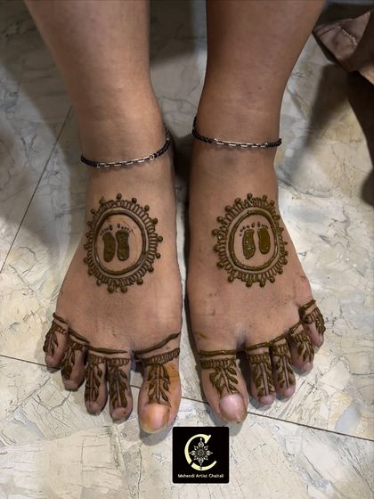Mehendi for the feet is a lovely addition for a baby shower. This simple and sweet design features tiny baby footprints inside a sun-like mandala on both feet.