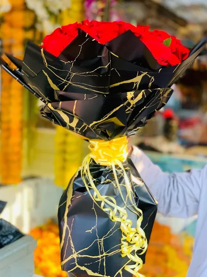 A side view of the 100-red-rose bouquet, emphasizing the stylish black and gold marble wrapping and the volume of the arrangement.