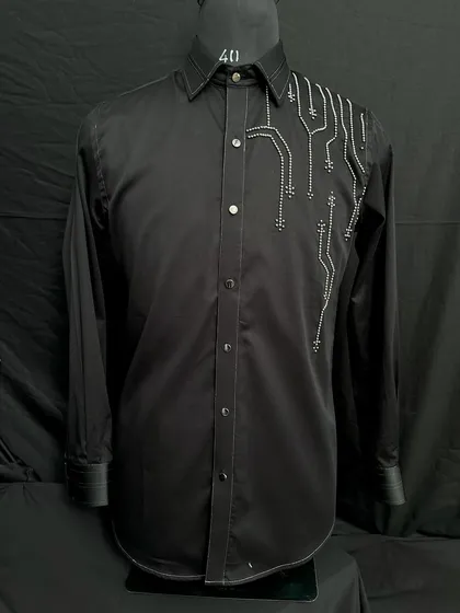 A black designer shirt with abstract, circuit-like embroidery in white thread. This piece is for the modern man who values unique, sophisticated design.