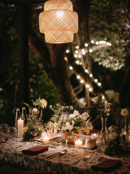 A beautifully set table at the welcome dinner. The printed tablecloth, white floral arrangements, and numerous candles created a cozy and inviting atmosphere under a canopy of trees.