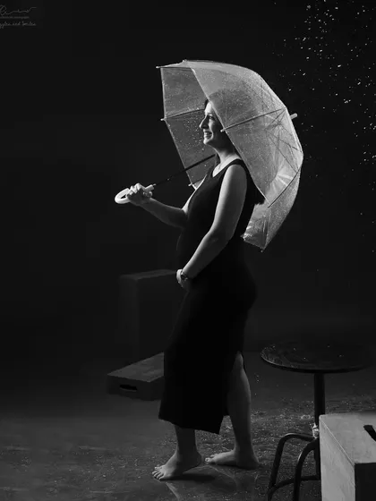 Who says you can't have rain in the studio? A simple umbrella prop adds a touch of playful storytelling to this classic black and white maternity portrait.