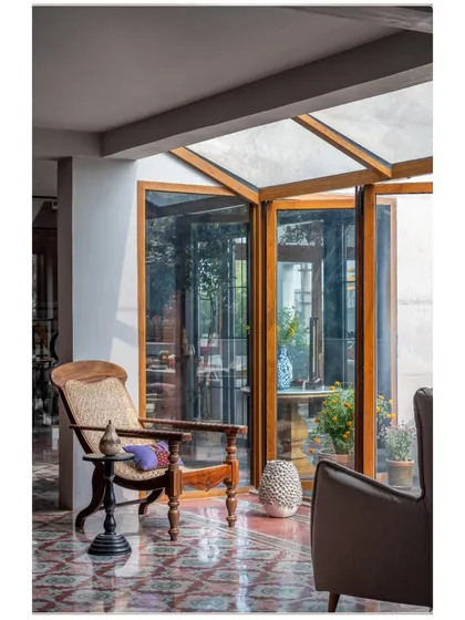 This quiet corner in the Dhaka residence is a perfect example of how light changes a space throughout the day. The antique-style chair, which traveled from Cochin, sits by a glass enclosure, blurring the line between inside and out. The patterned flooring was sourced from Mumbai, adding another layer to the home's story.