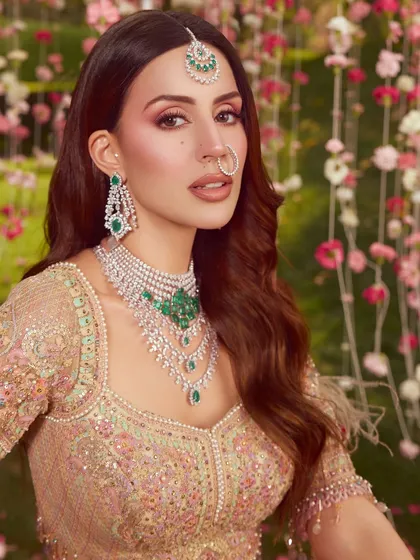 A beautiful portrait from a campaign shoot featuring a soft, ethereal bridal look. The makeup is focused on rosy tones and a luminous glow, set against a dreamy floral background.