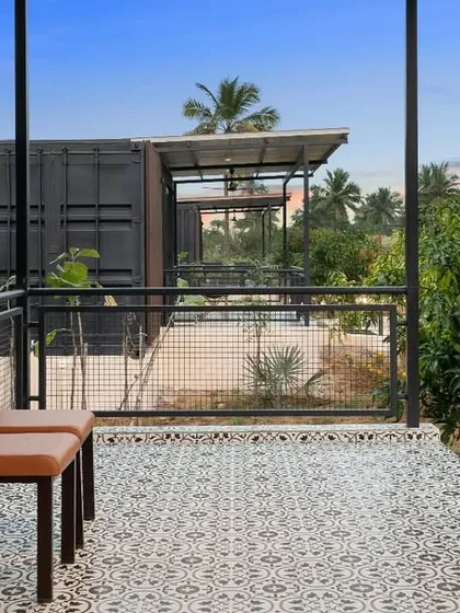 The balcony of a container villa, with patterned tiles and a view of the surrounding farm. This detail shot highlights the thoughtful design touches that make these homes unique.