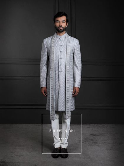 Every weave tells a tale. This light silver-grey silk sherwani carries the charm of timeless celebrations, layered with a fish-scale textured achkan and matching stole.