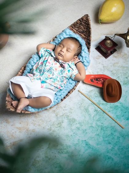 A peaceful newborn enjoying a nap on the beach, complete with a tiny hat and a fishing rod.