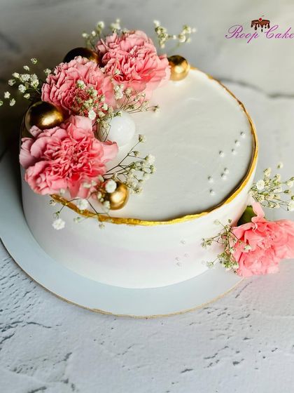 A pretty cake for a bride-to-be. This design features a delicate gold rim, fresh pink carnations, and baby's breath, creating a look of simple elegance.