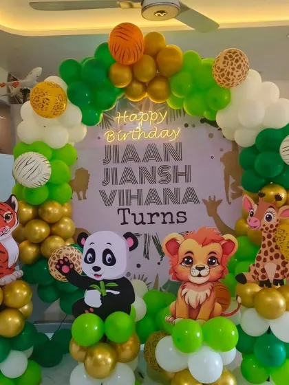 A jungle-themed birthday decoration for a home setting. This balloon arch features cute cutouts of a tiger, panda, lion, and giraffe, with a personalized "Happy Birthday" backdrop.