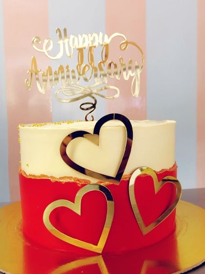 A stylish red and white two-tier anniversary cake. This design features a bold red base, a classic white top, and elegant gold heart accents.