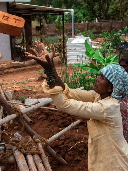 A moment of fluid motion on site. A woman mason expertly catches a brick, showcasing the rhythm and skill involved in the daily work of construction.